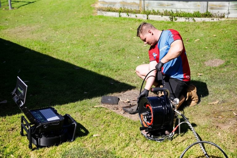 Plumber clearing a blocked drain in a Brisbane backyard
