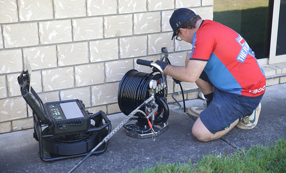 Plumber feeding a drain cable into a sewer line