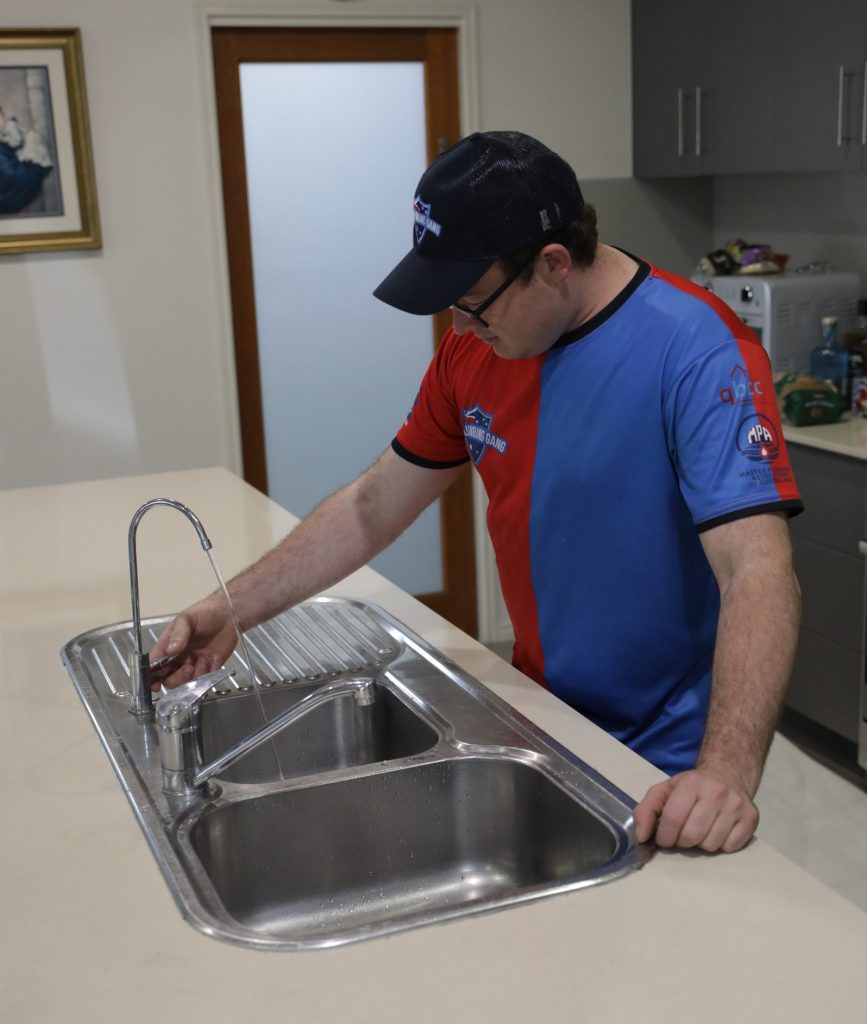 Plumber installing a kitchen sink mixer