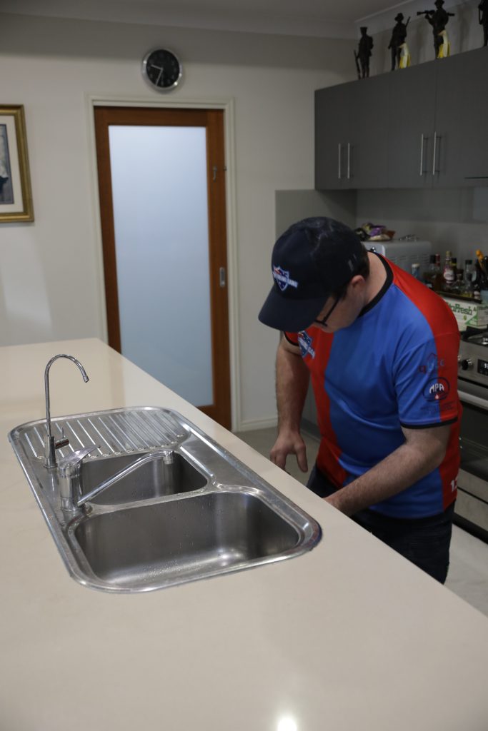 Plumber working on a stainless steel sink
