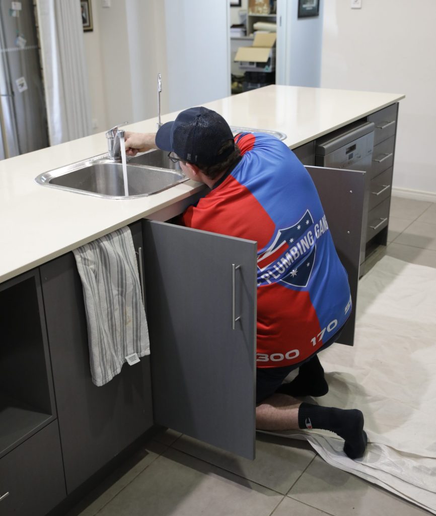 Plumber connecting a kitchen sink