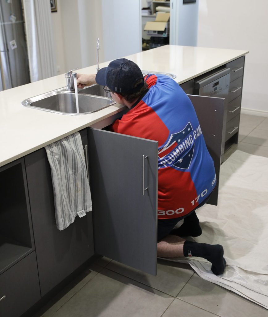 Plumber working under a kitchen cabinet