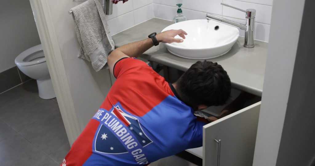 Plumber repairing a leaking bathroom vanity