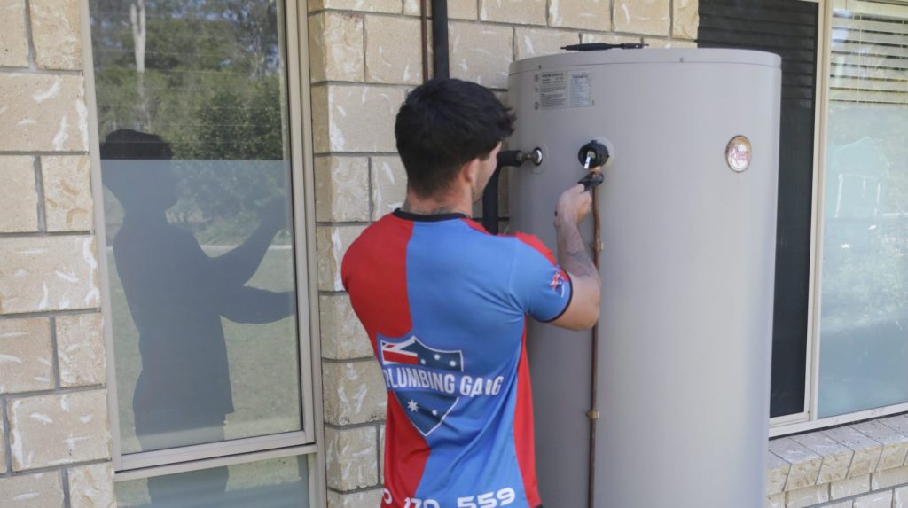 Plumber adjusting a hot water unit