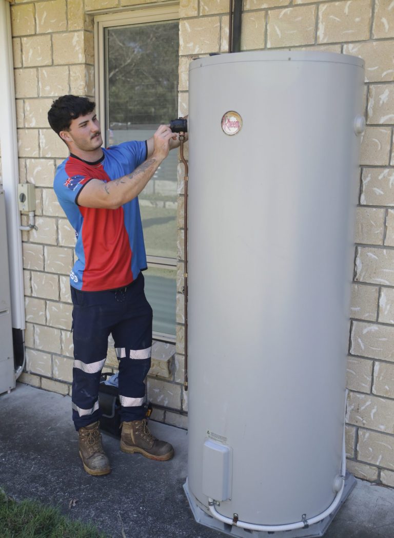 Plumber beside a replaced hot water system