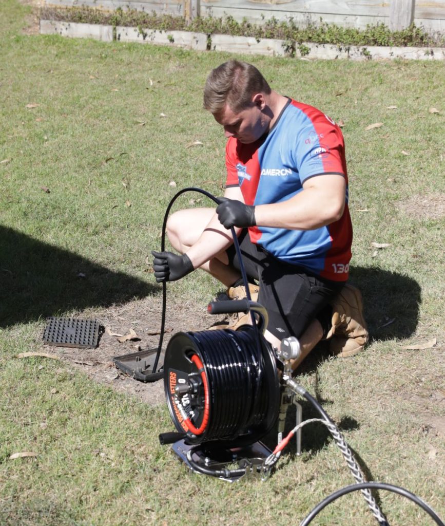 Plumber using drain clearing equipment