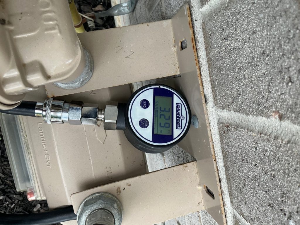 Gasfitter running a pressure test with a digital gauge