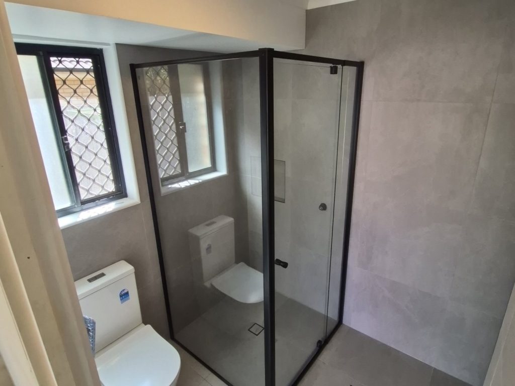 New black semi-frameless shower screen installed by The Plumbing Gang in a Brisbane bathroom